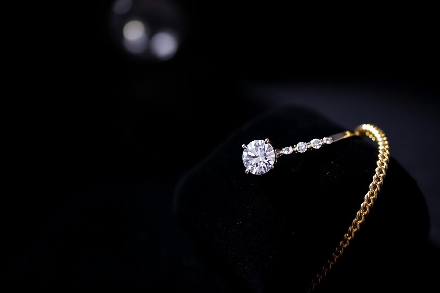Diamond engagement ring and gold bracelet on black velvet